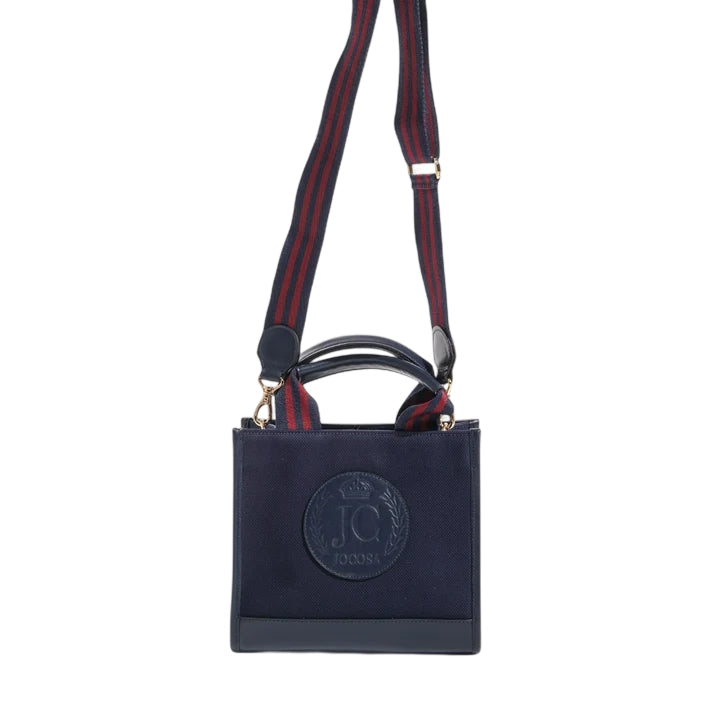 Front view of the JOCOSA Club Tote in navy canvas with navy leather trim, an embossed leather logo, navy and bordeaux striped handles and a matching detachable shoulder strap with gold-tone hardware.