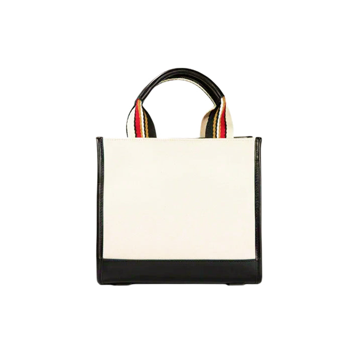 Back view of the JOCOSA Club Tote in ivory canvas with black leather trim, black, red and ivory striped handles, reinforced leather base and structured rectangular silhouette.
