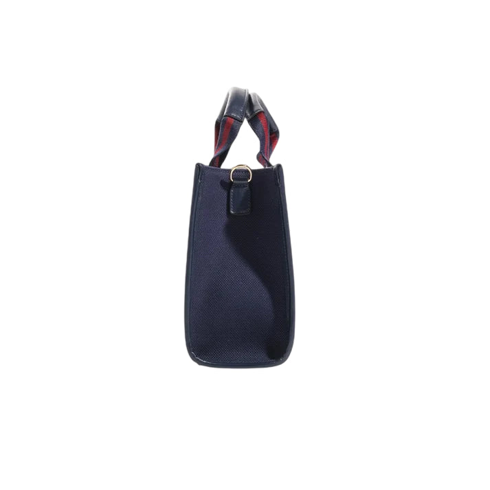 Side view of the JOCOSA Club Tote bag in navy canvas with navy leather trim, navy and bordeaux striped handles and gold-tone hardware.