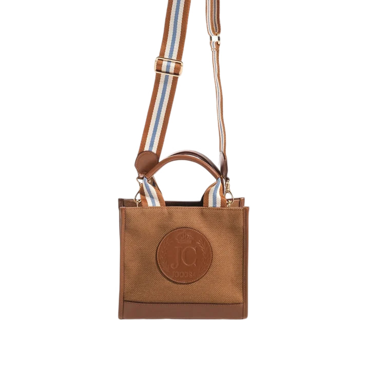 Front view of the JOCOSA Club Tote in camel canvas with camel leather trim, an embossed leather logo, camel, ivory and blue striped handles and a matching detachable shoulder strap with gold-tone hardware.