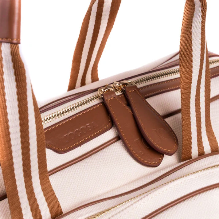Close-up of the JOCOSA Club Bag in ivory canvas with camel leather trim, camel and ivory striped handles, gold-tone zippers and embossed leather zipper pulls.